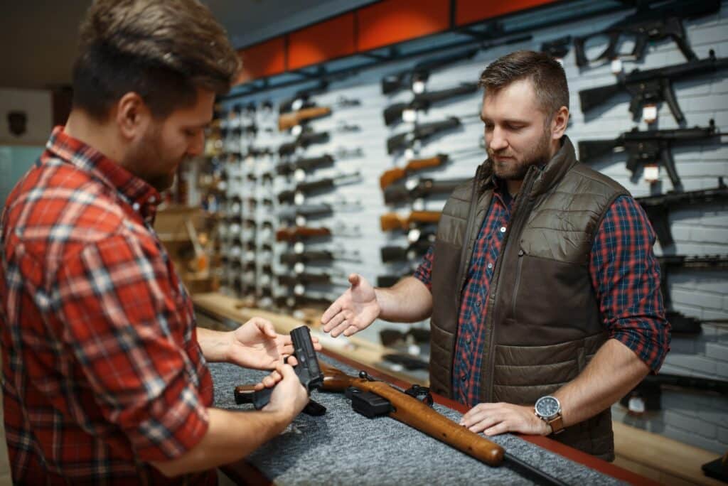 Man with owner choosing handgun in gun shop